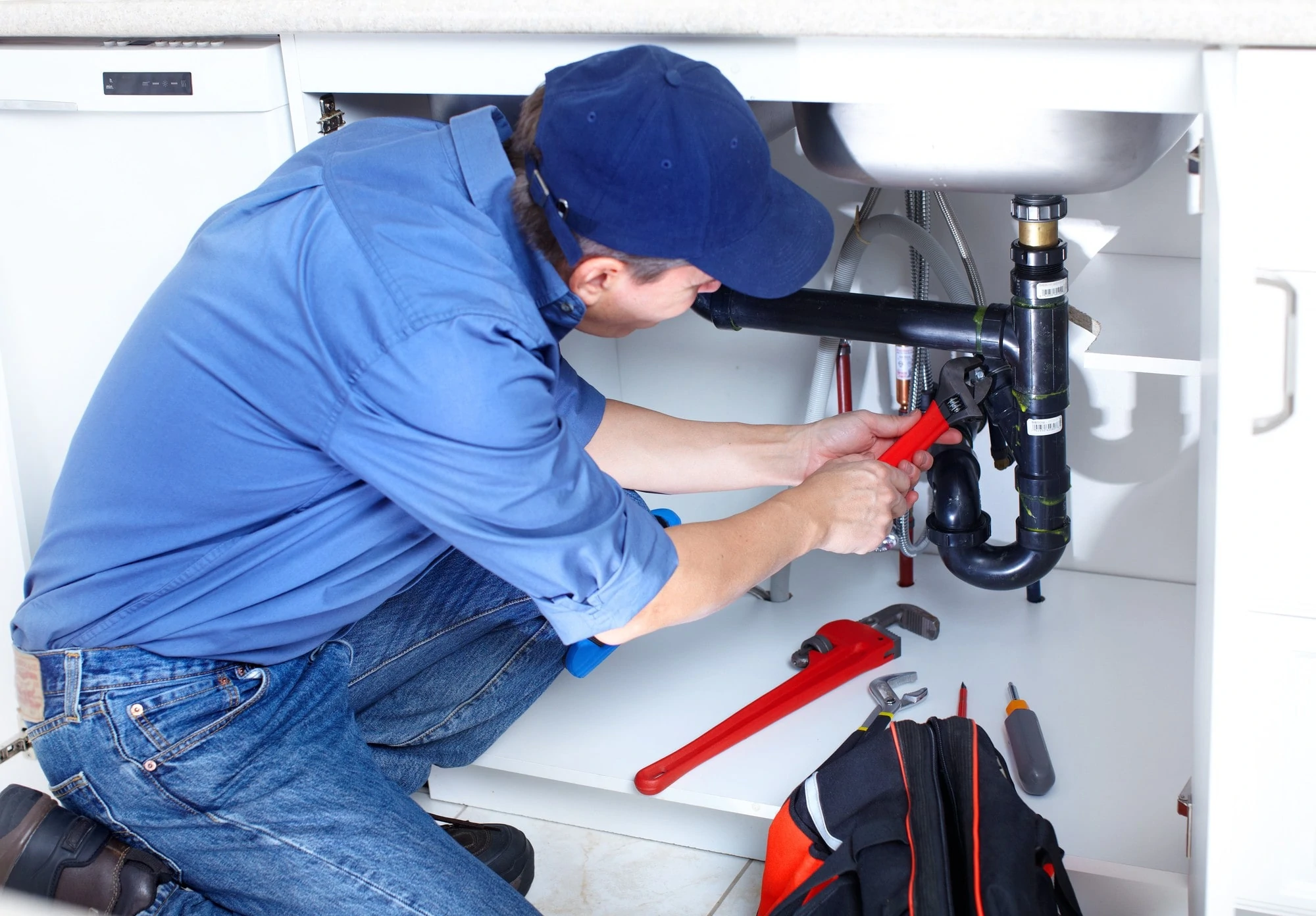 Plumber Fixing A Sink At Kitchen